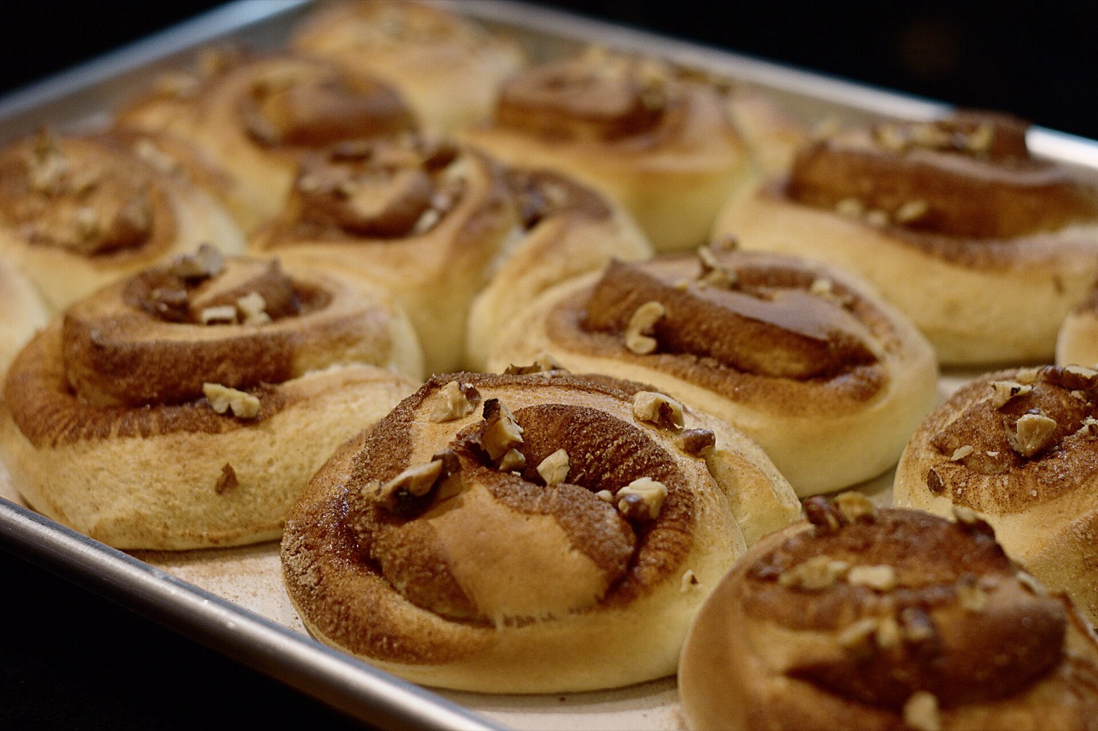 A tray of fresh cinnamon buns topped with pecans