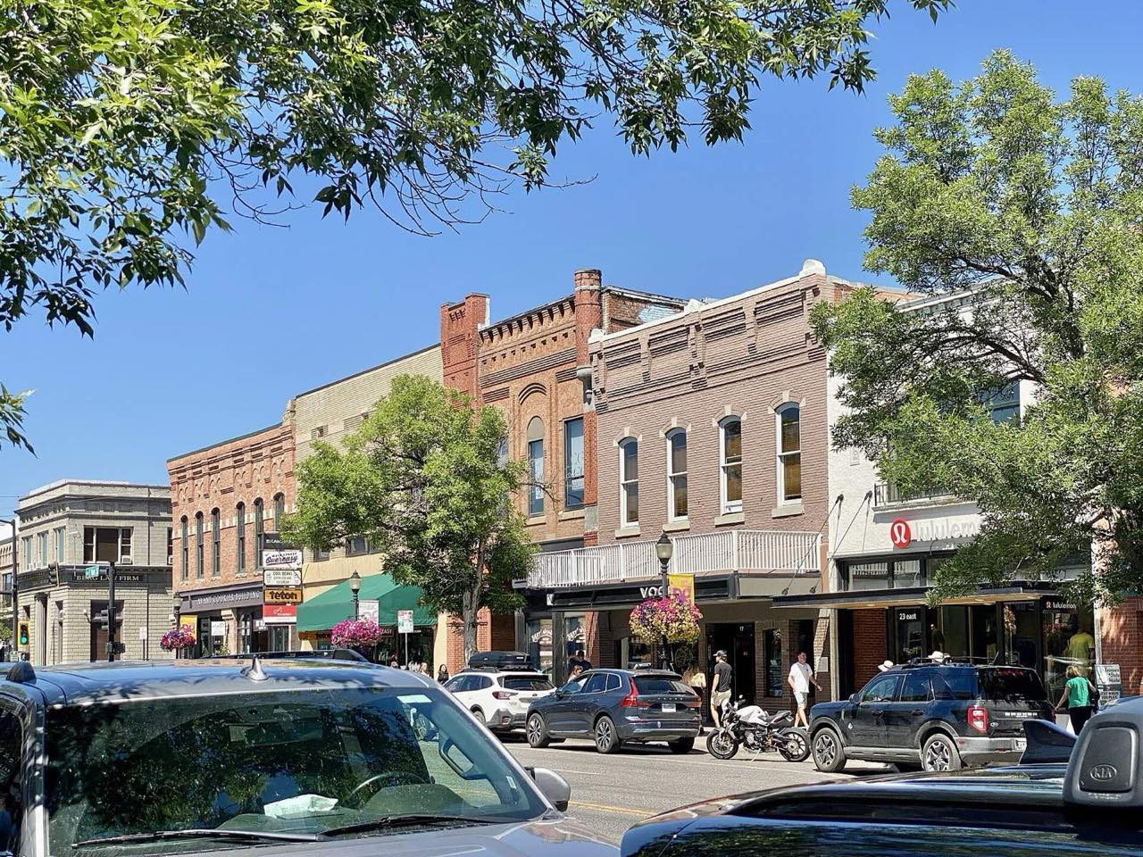 Historic brick storefronts and leafy trees along Main Street in downtown Bozeman